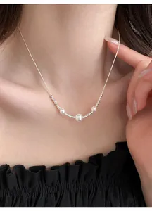 Elegant silver necklace with three pearls on a delicate chain, close-up worn view.