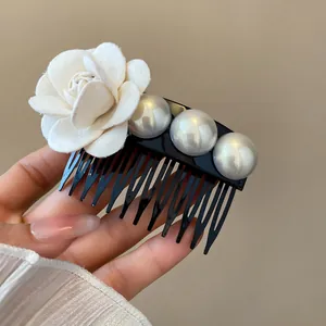 Detail view of a French style hair comb featuring white fabric flower and three elegant pearls.