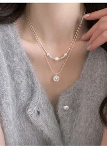 Close-up view of an elegant double-layered silver necklace with pearls and star pendant