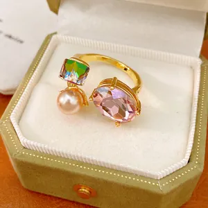 Close-up of elegant gold-plated open ring with pink gem and pearl in jewelry box