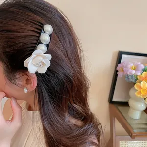 Close-up detail of a French style fabric flower and pearl hairpin worn on long wavy hair