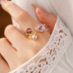 Detailed macro view of adjustable gold ring featuring pink oval crystal and white pearl