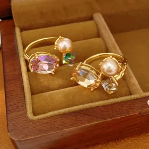 Detailed macro view of gold-tone open rings featuring faceted oval crystals and pearls