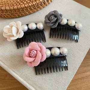 Detail view of three fabric flower hair combs with elegant pearls in various colors.