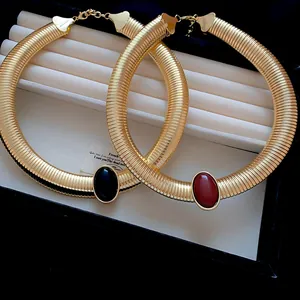 Gros plan de colliers torque dorés vintage avec résine ovale noire et rouge