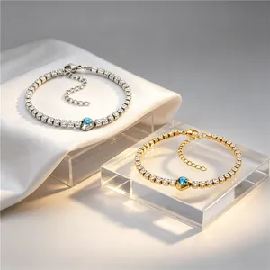 Detail view of gold and silver tennis bracelets with a central blue square zircon.