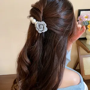 Close-up of an elegant fabric rose and pearl hairpin worn on beautifully styled hair
