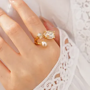 Detailed view of elegant gold plated open ring with oval crystal and pearl on model finger.