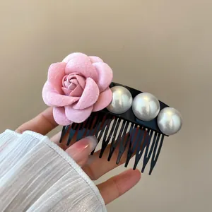Detail shot of a French fabric rose hair comb with elegant white pearls on a black base