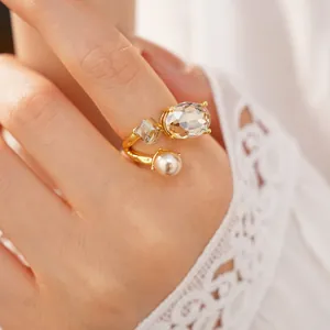 Close-up view of an elegant gold open ring featuring oval crystal and pearl detailing.
