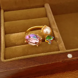 Macro view of gold open ring featuring oval purple gem, rainbow cube and pearl detail