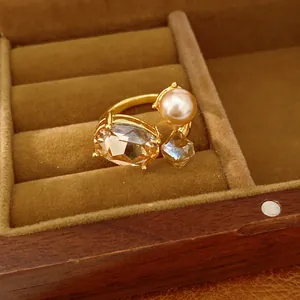 Detailed view of an open ring with oval and square champagne stones and a pearl.