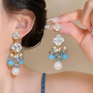 Close-up of elegant blue beaded tassel earrings with faceted crystals and large white pearls.
