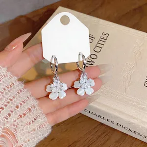 Elegant zircon flower hoop earrings featuring white shell petals in a vintage book setting