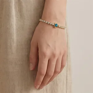Detailed shot of a gold titanium steel bracelet featuring a blue heart-shaped zircon.