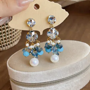 Detail close-up of fresh blue beaded tassel earrings with white pearls and crystal studs