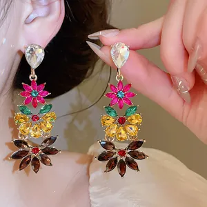 Close-up detail of colorful floral crystal drop earrings with vibrant multi-tier gems.