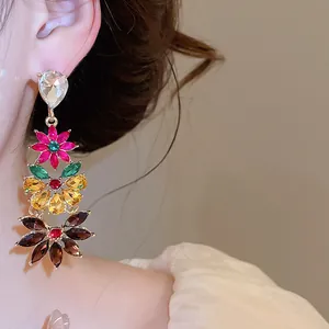 Detailed view of colorful crystal flower drop earrings worn by a model