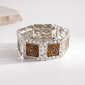 Close-up of retro silver bracelet with amber enamel spiral pattern and dot texture