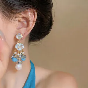 Close-up of elegant long tassel earrings with blue beads and pearls