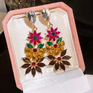 Detailed close-up view of colorful rhinestone flower dangle earrings in a pink box