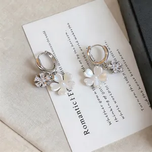 Close-up of elegant flower hoop earrings with shell petals and zircon charms