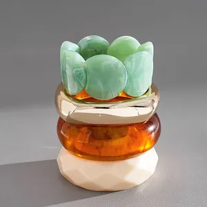 Gros plan de bracelets empilés en acrylique marbré vert et ambre avec un anneau doré
