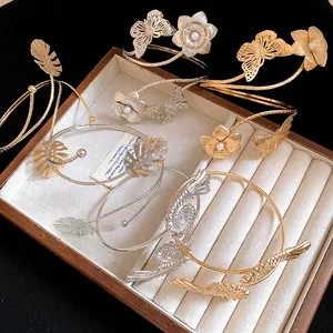 Detailed view of gold and silver metallic leaf and flower arm cuffs on a jewelry tray