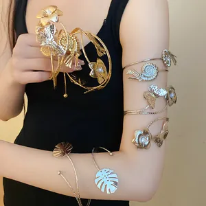 Detail view of stylish gold and silver metal arm cuffs with leaf and butterfly designs