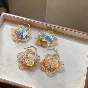 Vue détaillée d'élégantes boucles d'oreilles fleurs ajourées avec perles colorées