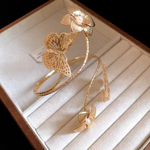 Detailed macro view of a golden butterfly and flower armlet resting inside a plush jewelry box
