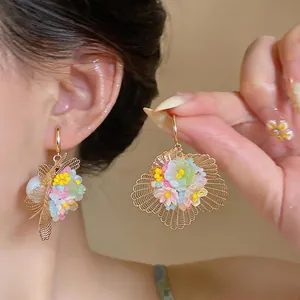 Gros plan de boucles d'oreilles fleuries 3D avec un design doré ajouré complexe