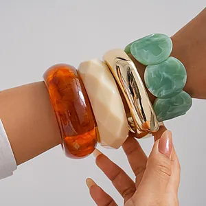 Détail de joncs géométriques en acrylique et d'un bracelet à maillons marbrés