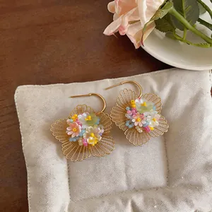 Vue détaillée de boucles d'oreilles fleurs évidées dorées avec perles colorées