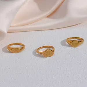 Detailed view of three 18K gold-plated stainless steel signet rings with funny engravings.