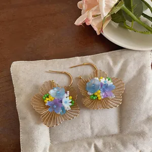 Vue détaillée de boucles d'oreilles fleurs ajourées avec pétales colorés sur un coussin