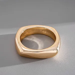 Gros plan d'un bracelet jonc géométrique minimaliste au fini doré poli et brillant.