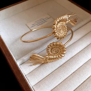Detailed close-up of a gold metal nautilus spiral arm cuff bracelet in jewelry box