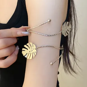 Close-up of minimalist metal Monstera leaf arm cuff bracelet worn on female upper arm