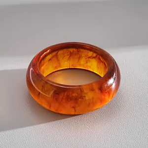 Gros plan détaillé d'un bracelet en acrylique ambré marbré avec effets d'ombre et lumière