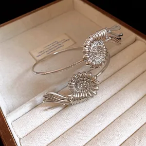 Detailed view of a silver metal arm cuff with intricate shell-like decorative motifs