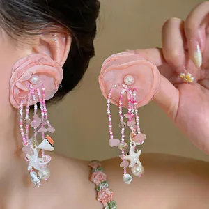 Gros plan de boucles d'oreilles fleur rose avec perles et breloques étoile