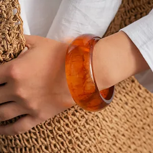 Gros plan d'un large bracelet jonc en résine acrylique ambrée avec joli motif marbré