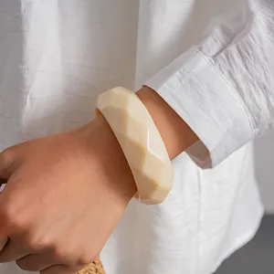 Vue détaillée d'un bracelet jonc géométrique en acrylique crème sur le poignet d'une femme