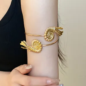 Detailed view of a stylish gold metal spiral ammonite arm cuff bracelet on a model