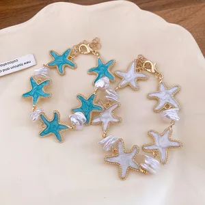 Nahaufnahme goldener Seestern-Armbänder mit türkisfarbenen und weißen Anhängern und Barockperlen.