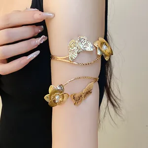 Detailed macro view of golden butterfly and flower arm cuff bracelet worn on the upper arm
