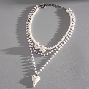 Dettaglio della collana di perle multistrato con fiori di strass e pendente a cuore