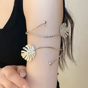 Close-up view of a minimalist metal monstera leaf armlet worn on the upper arm of a model