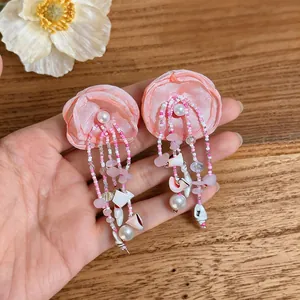 Gros plan détaillé de boucles d'oreilles fleurs en tissu rose avec perles et coquilles